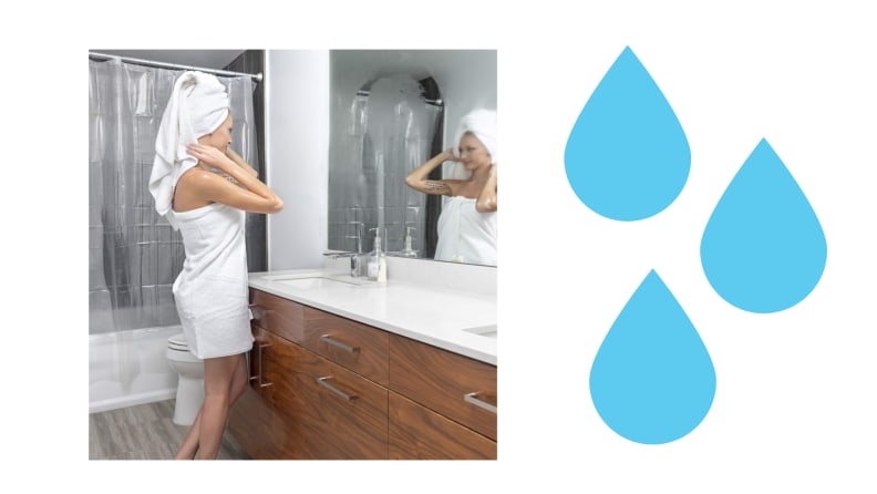 A woman stands next to a clear shower curtain in a bathroom
