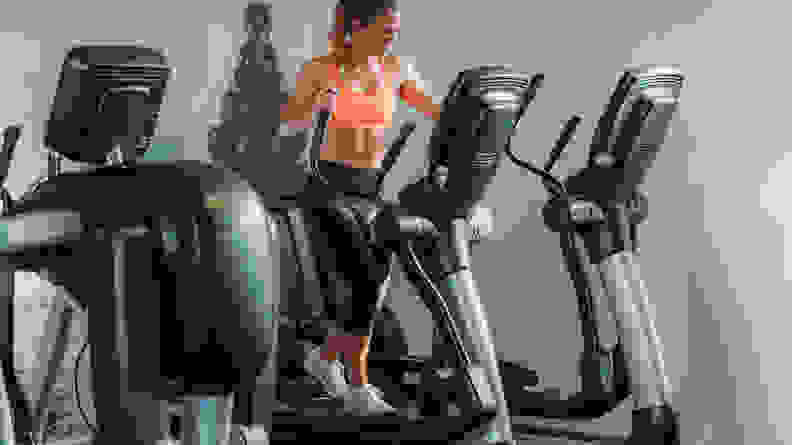 A woman using the elliptical at the gym.