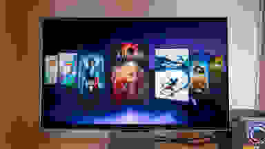 A 3D gaming monitor sits on a desk with video games gallery on its screen
