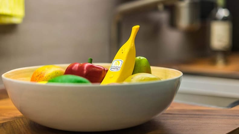 A banana phone sitting in a full fruit bowl