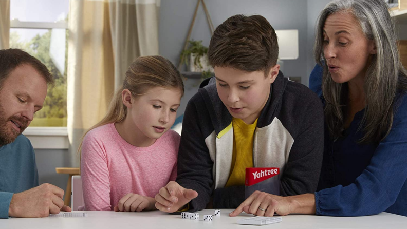 A family of four plays Yahtzee.