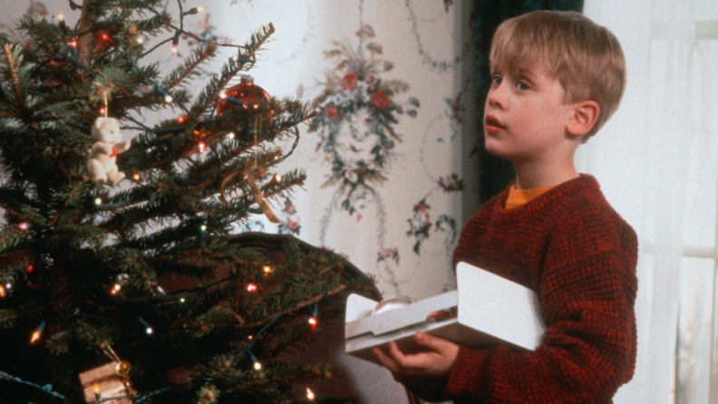 Kevin McCallister is the protagonist of 1990's Home Alone. He looks on from a dressed Christmas tree the day before being forgotten by his parents, played by the legendary Catherine O'Hara and John Heard.