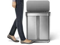 A woman's foot steps on the pedal bar to open the Simplehuman dual compartment trash can.
