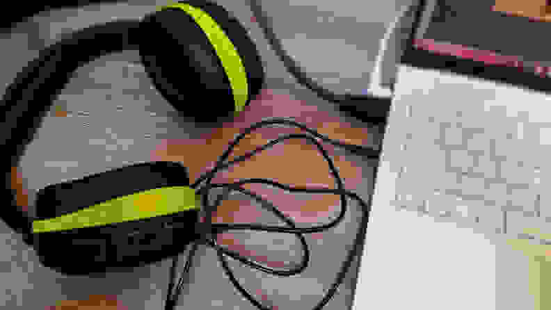 A pair of black headphones (with green-yellow accents) is plugged into a laptop.
