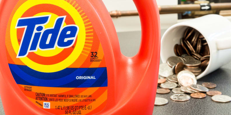 Tide Original liquid laundry detergent with a mug in the background filled with spilling coins.
