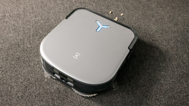The Ecovacs Deebot X2 Omni on gray carpet cleaning macaroni