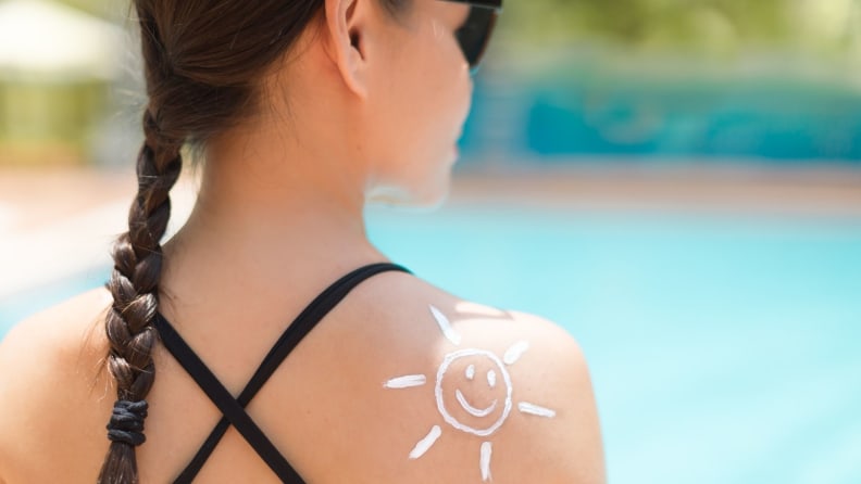 A girl with a sun drawn on her back in sunscreen