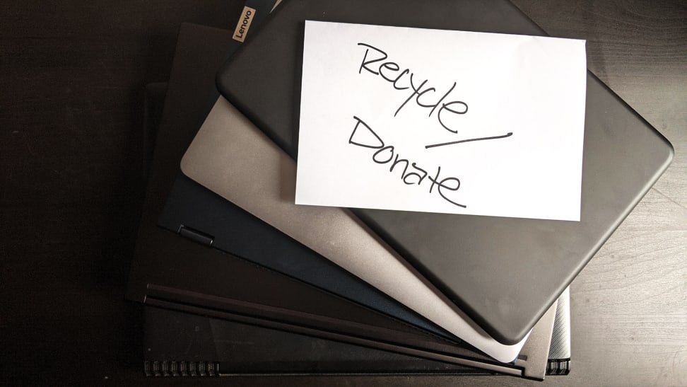 A handwritten note on top of a stack of laptops asking people to recycle and donate their old laptops