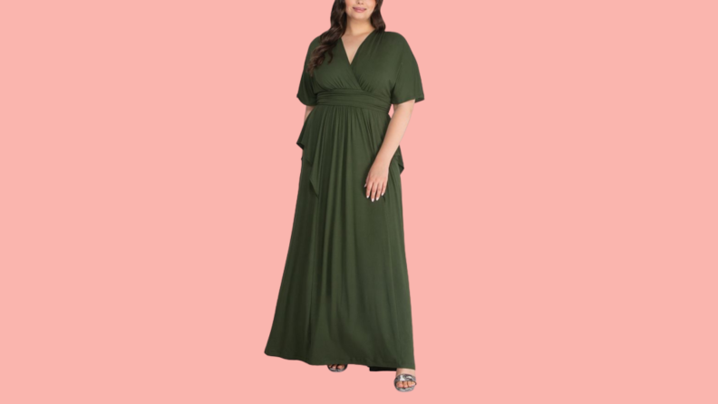 A woman wears a green maxi dress with a peplum waist.