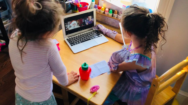 Two children watch Santa Claus on a laptop.