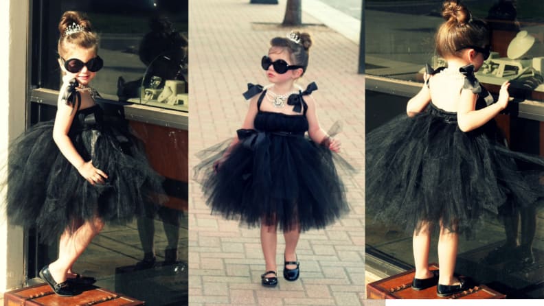 Child dressed up in Audrey Hepburn Halloween costume outdoors.