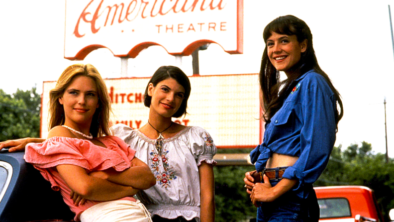 Three high-school-senior girls are hanging out in front of the Americana Theatre in Austin, Texas, in the film Dazed and Confused.
