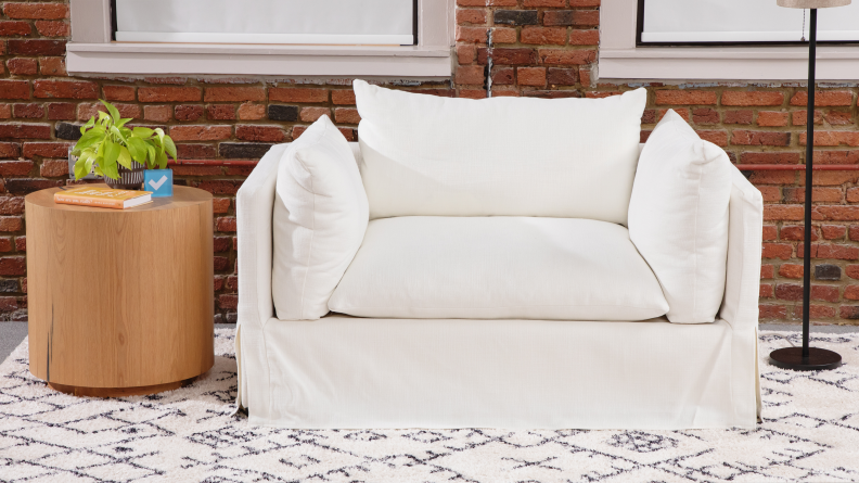 A white couch with a circular oak table next to it.