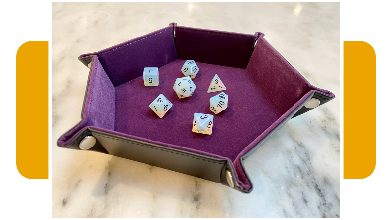 Hexagon dice tray with purple cloth interior and several dice inside.