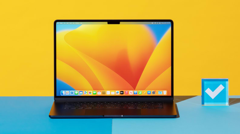 Ноутбук MacBook Air 15 M2 черного цвета стоит на синей поверхности рядом с акриловым пресс-папье с заставкой на экране.