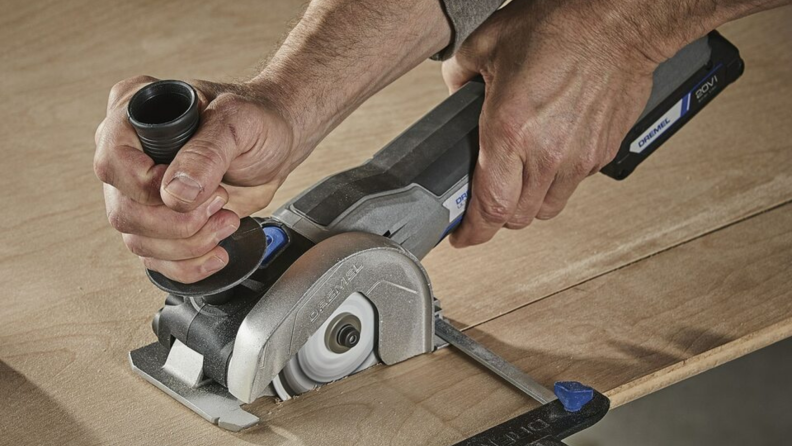 A person uses the Dremel US20V Ultra-Saw to cut wood.