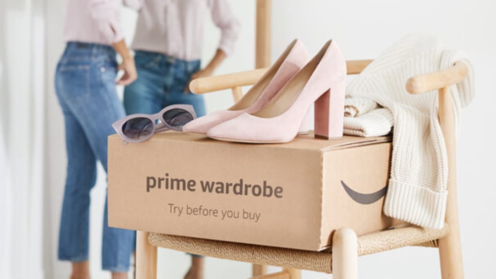 A woman wearing jeans looking in the mirror with a Prime Wardrobe box with a pink pair of heels on top
