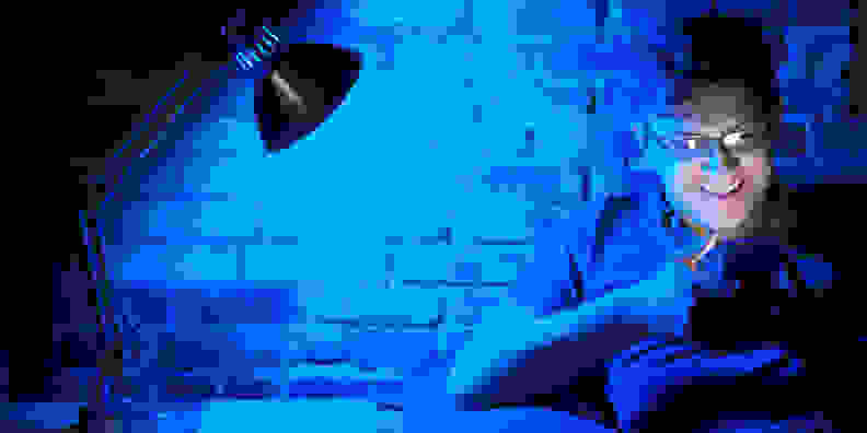 A person sits under a blue light