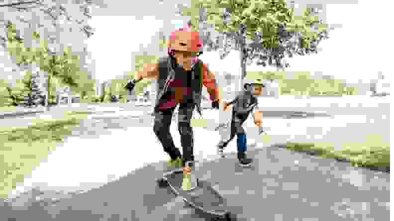 Two boys ride on a walkway on their skateboards.