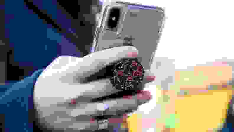 A person uses a mobile phone with a Popsocket.