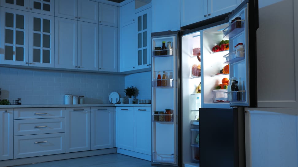 An opened fridge at nighttime, filled with food