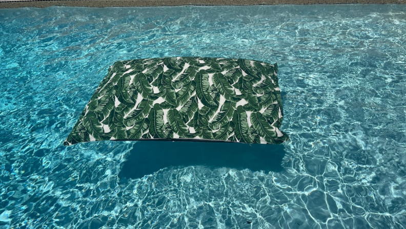 Empty Laze Pillow pool float in a fiddle leaf print floating in blue pool water.