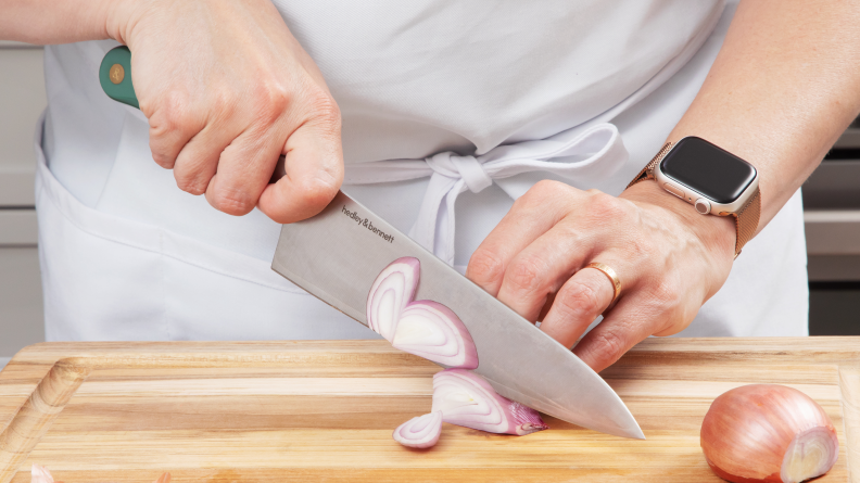 Person using Hedley & Bennett chef's knife to slice shallot