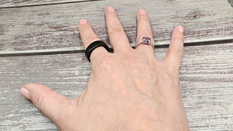 Noise Luna Ring and a wedding ring on fingers of a hand on a wooden surface