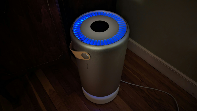 The Molekule air purifier glows with a blue UV light ring around the top.
