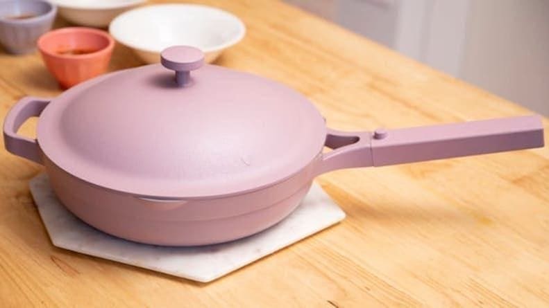 A light pink Always Pan, sitting on top of a wooden counter.