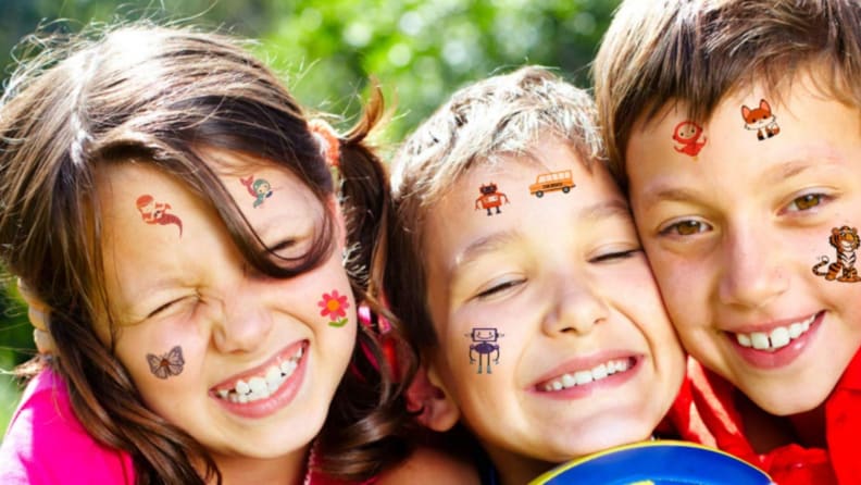 Three children with faces covered in silly temporary tattoos.