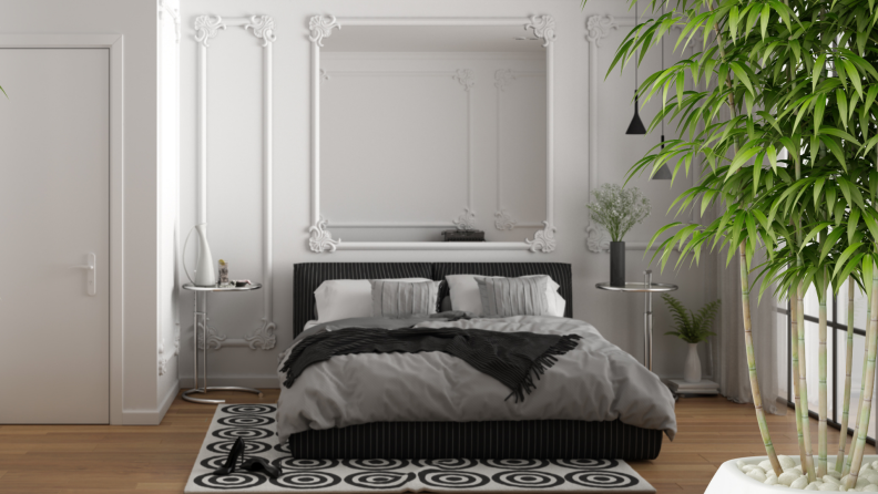 A minimalistic bedroom surrounded by green plants and a massive mirror above a bed.