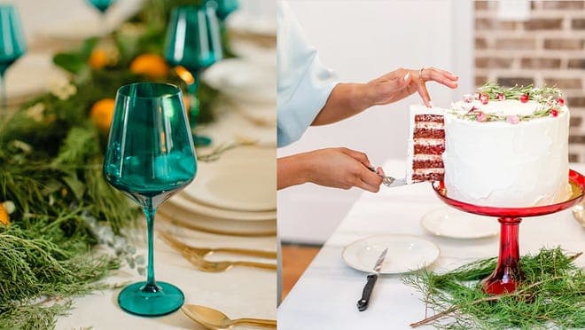 A teal wine glass and a red glass cake stand, holding a white cake.