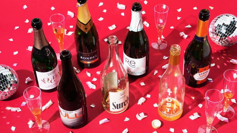 Several bottles of opened champagne alternatives on a red background with confetti and disco balls
