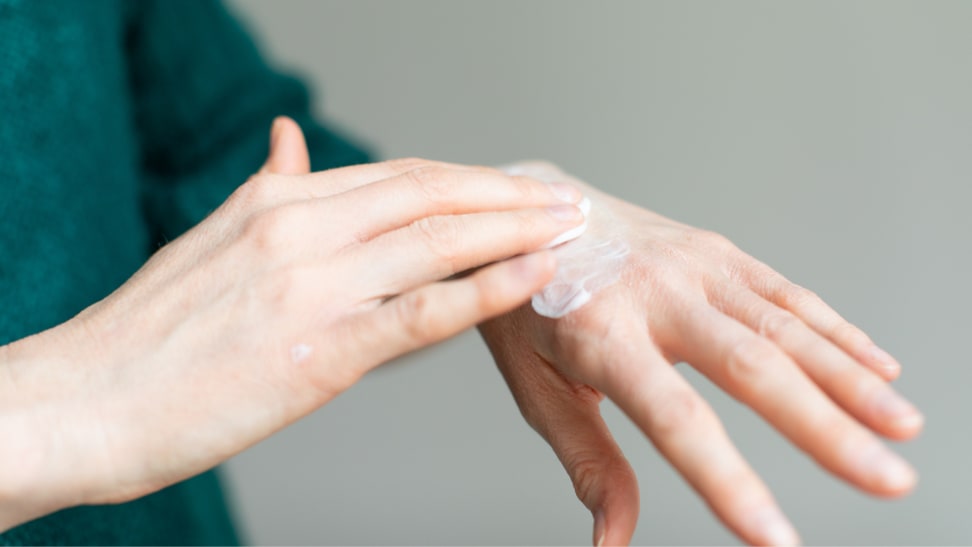 Person using hands to rub moisturizer into skin.
