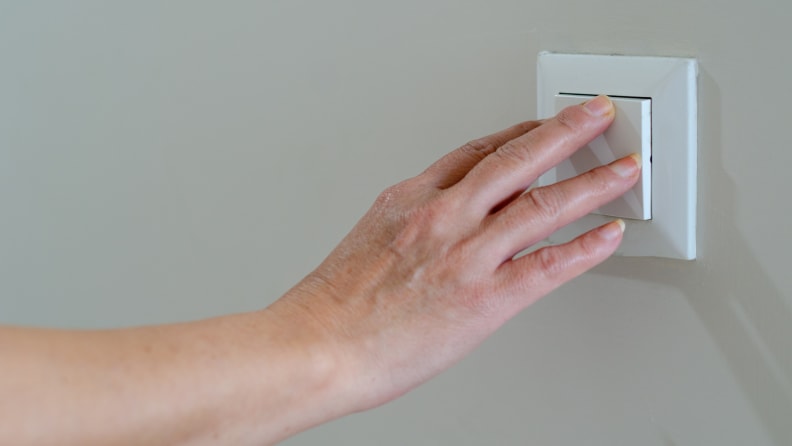 Person using hand to turn off light switch.