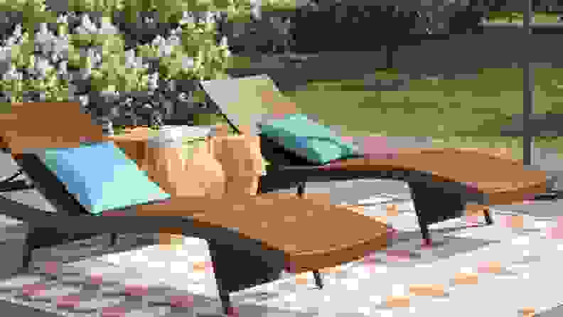 Two wooden chaise lounges sit on a sunny patio.