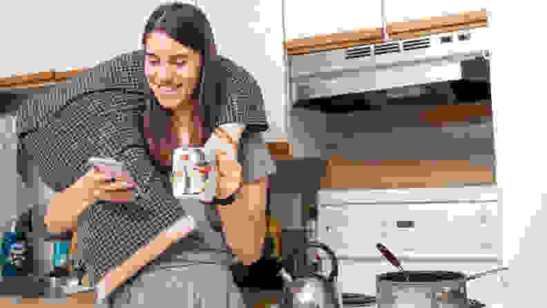 A woman standing in a kitchen wearing the Boyfriend pillow around her neck