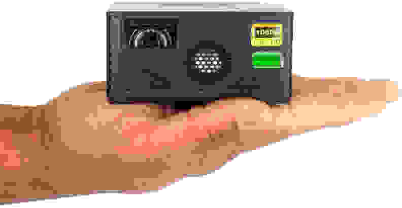 A outstretched hand holds the small AAXA P400 mini projector.