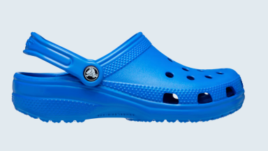 a classic blue Croc clog sits on a light blue background