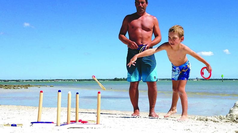 People play ringtoss on a beach.