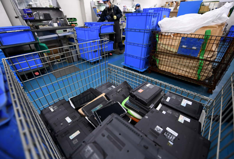 Laptops, die in einem Einkaufswagen in einer Recyclinganlage gestapelt sind