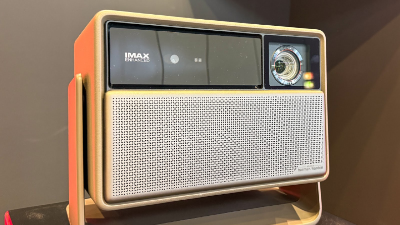 An XGIMI Horizon 20 series projector is displayed on a stand under bright lighting. The front panel shows the IMAX Enhanced logo alongside the lens, with a silver perforated speaker grille.