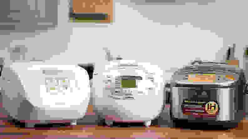 Three rice cookers sitting on a table.