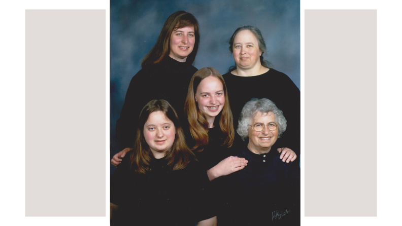 A studio family portrait featuring five women, all of whom are dressed in black. The clothing worn by the three seated individuals blends into the black shirts worn by the standing two figures in the back so the three heads appear to be floating.