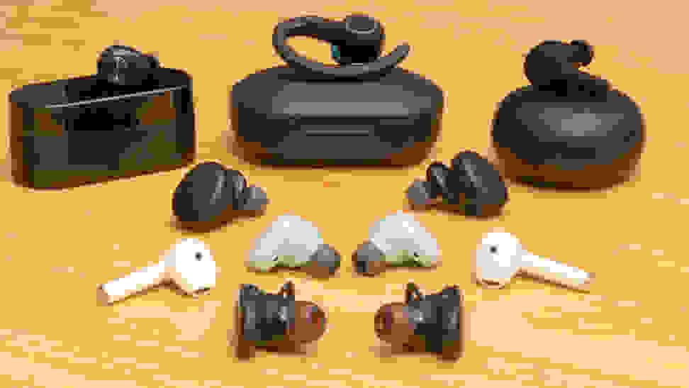 A bunch of different true wireless earbuds side by side on a table