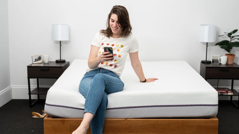 a person sits on the edge of a bed on their phone