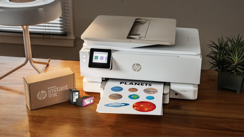 Lifestyle image of a home printer on a tabletop with a box of HP Instant Ink next to it.