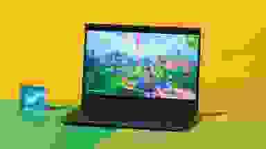 The Alienware m16 R2 gaming laptop with a video game scene on screen on top of a two-tone green surface.