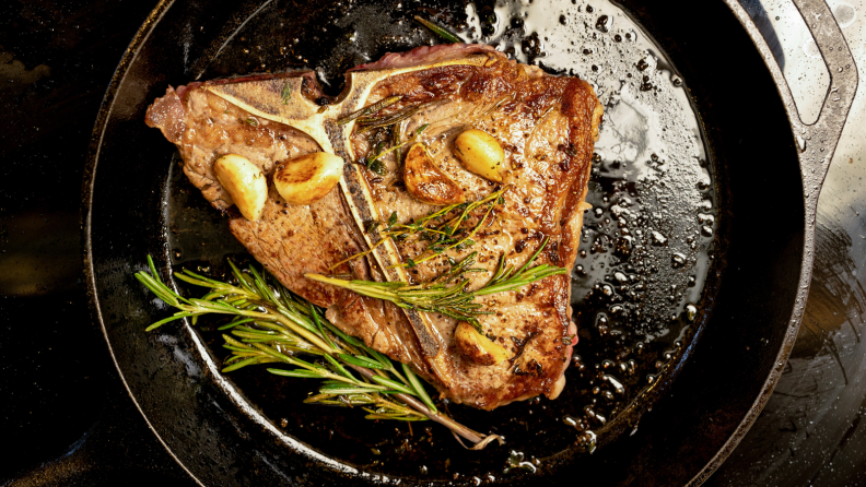 A piece of pork chop seared in a cast iron skillet.